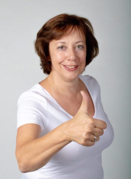 Freundlich lächelnde Frau mit Daumen hoch – Symbol für positives, erfolgreiches Mahnen am Telefon im ANKH.AT Kommunikations-Training.